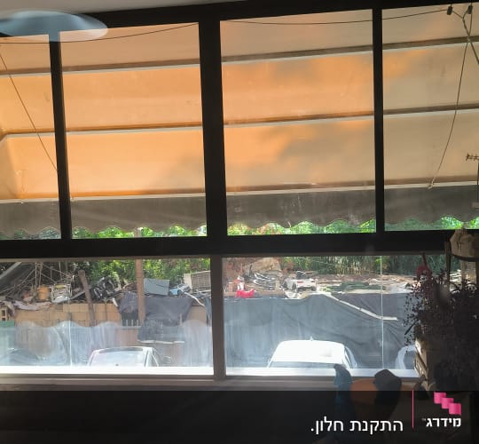 חלון גדול עם וילון כתום ואור שמש
